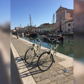 A waterfront with boats docked, a paved walkway, and buildings in the background. - CasaDodici (Cesenatico)