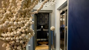 Un couloir agrémenté d’une composition décorative d’objets sphériques, d’un lustre et d’une porte à motifs.