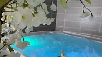 Un área de piscina con agua azul cristalina, rodeada de flores blancas y follaje verde.