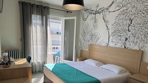 Una habitación de hotel con cama, mesita de noche y vistas al balcón exterior.