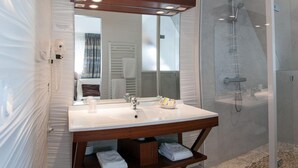 A modern bathroom with a large mirror, a wooden vanity, a shower enclosure, and a tiled floor. - Du Casino (Vierville-sur-Mer)