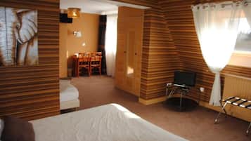 A hotel room with a bed, a television, a seating area with chairs, and a wooden wall design.