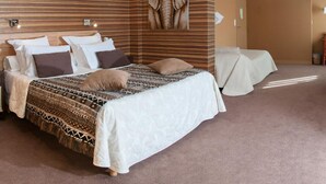 A spacious bedroom with a large bed, a wooden accent wall, and a mounted artwork of an elephant. - Du Casino (Vierville-sur-Mer)