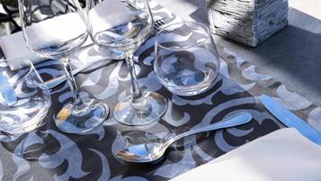 A table set with wine glasses, a fork, a knife, and a napkin, with a small potted plant on the table.