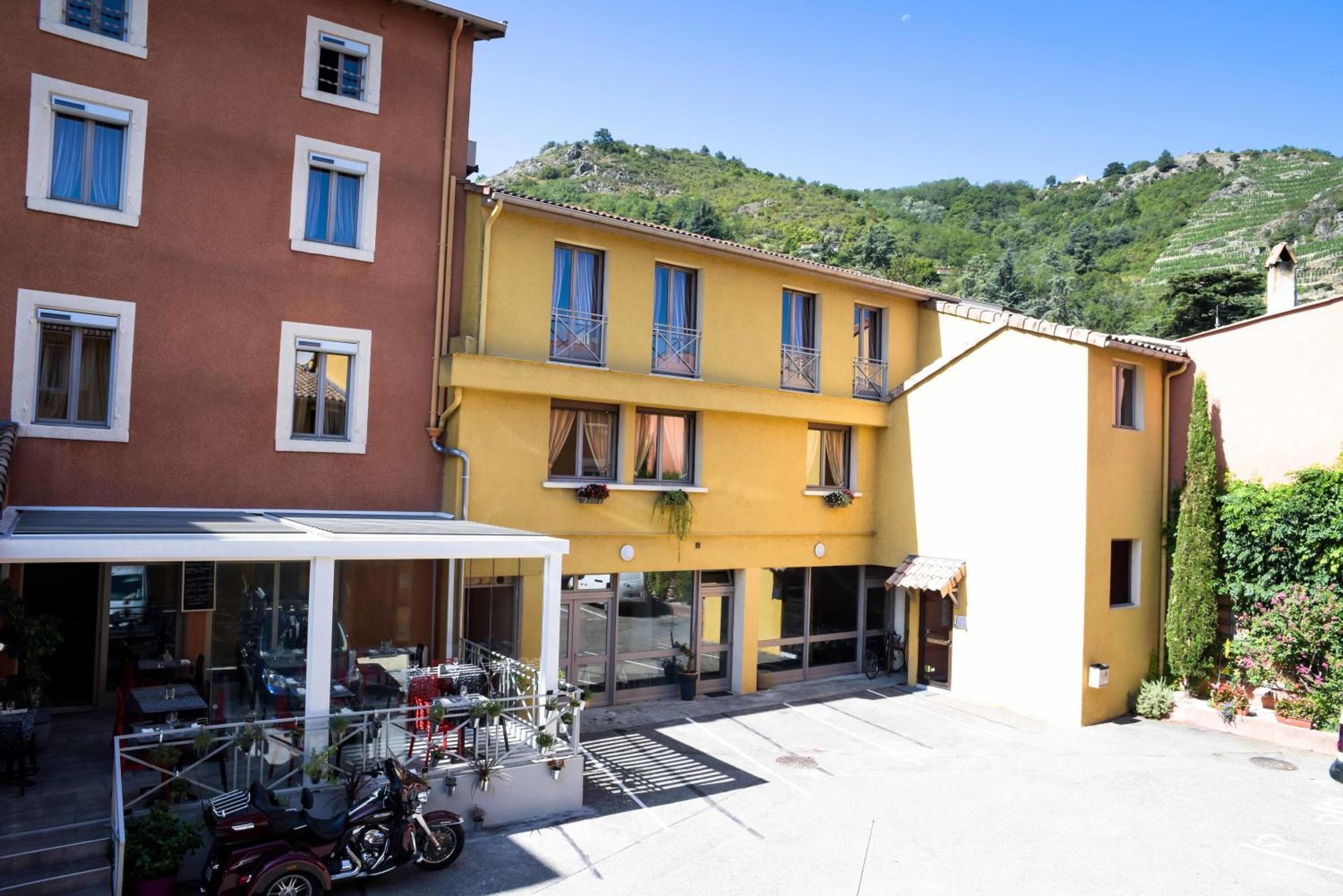 A yellow building with a covered outdoor seating area and a motorcycle parked in front.