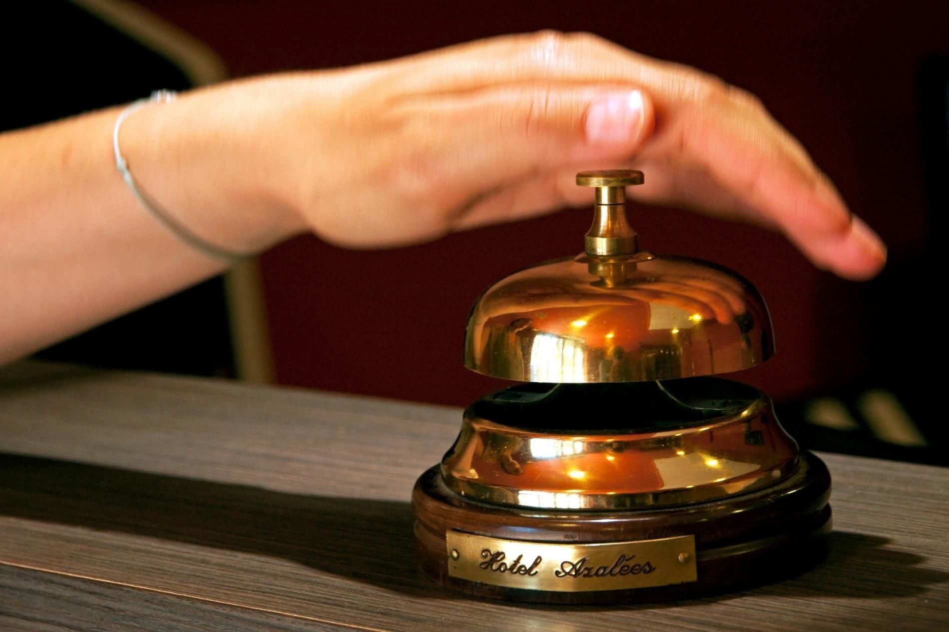 Uma mão pressionando um sino de hotel.