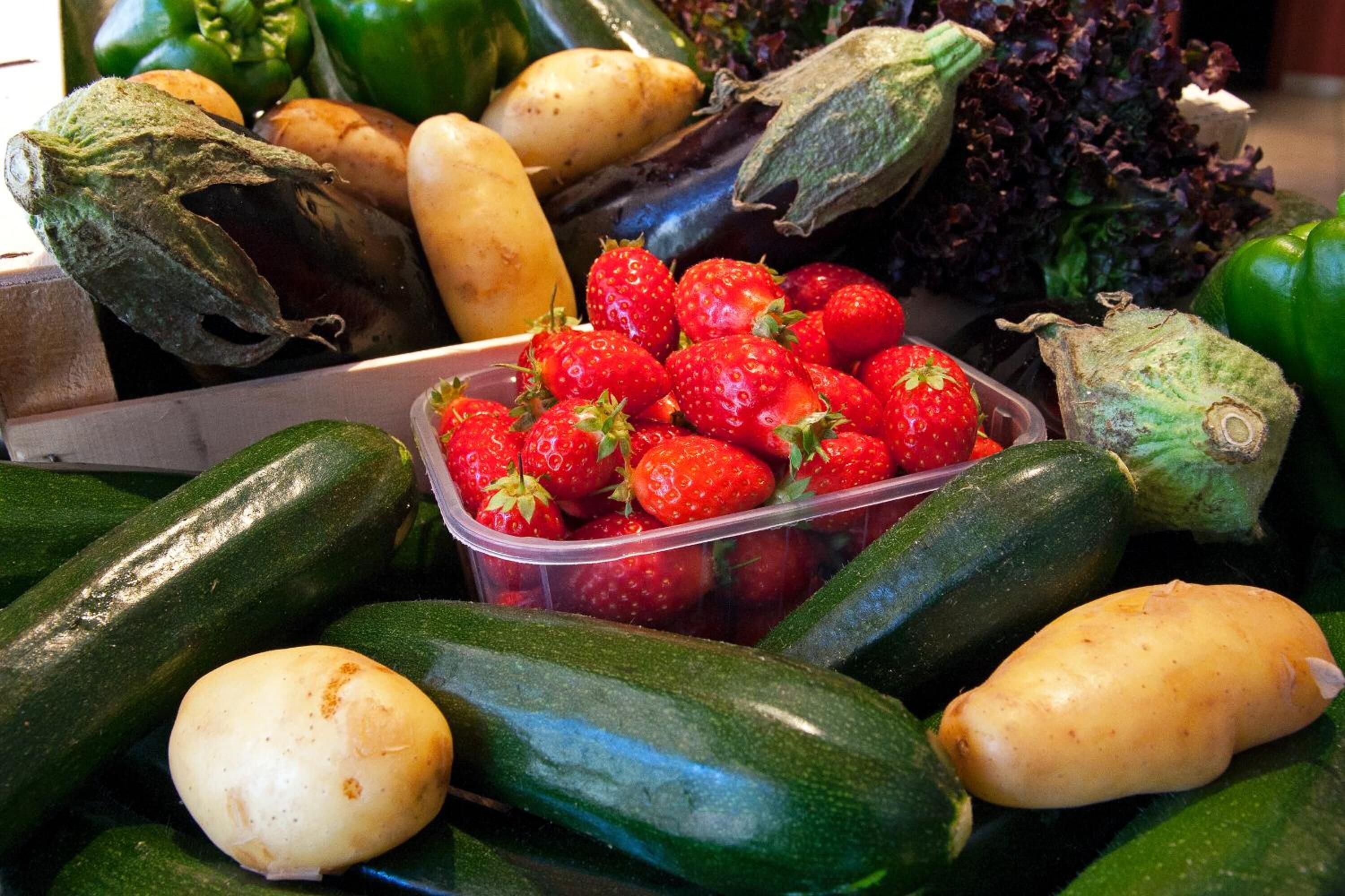 A variety of fresh produce including cucumbers, potatoes, strawberries, and lettuce.