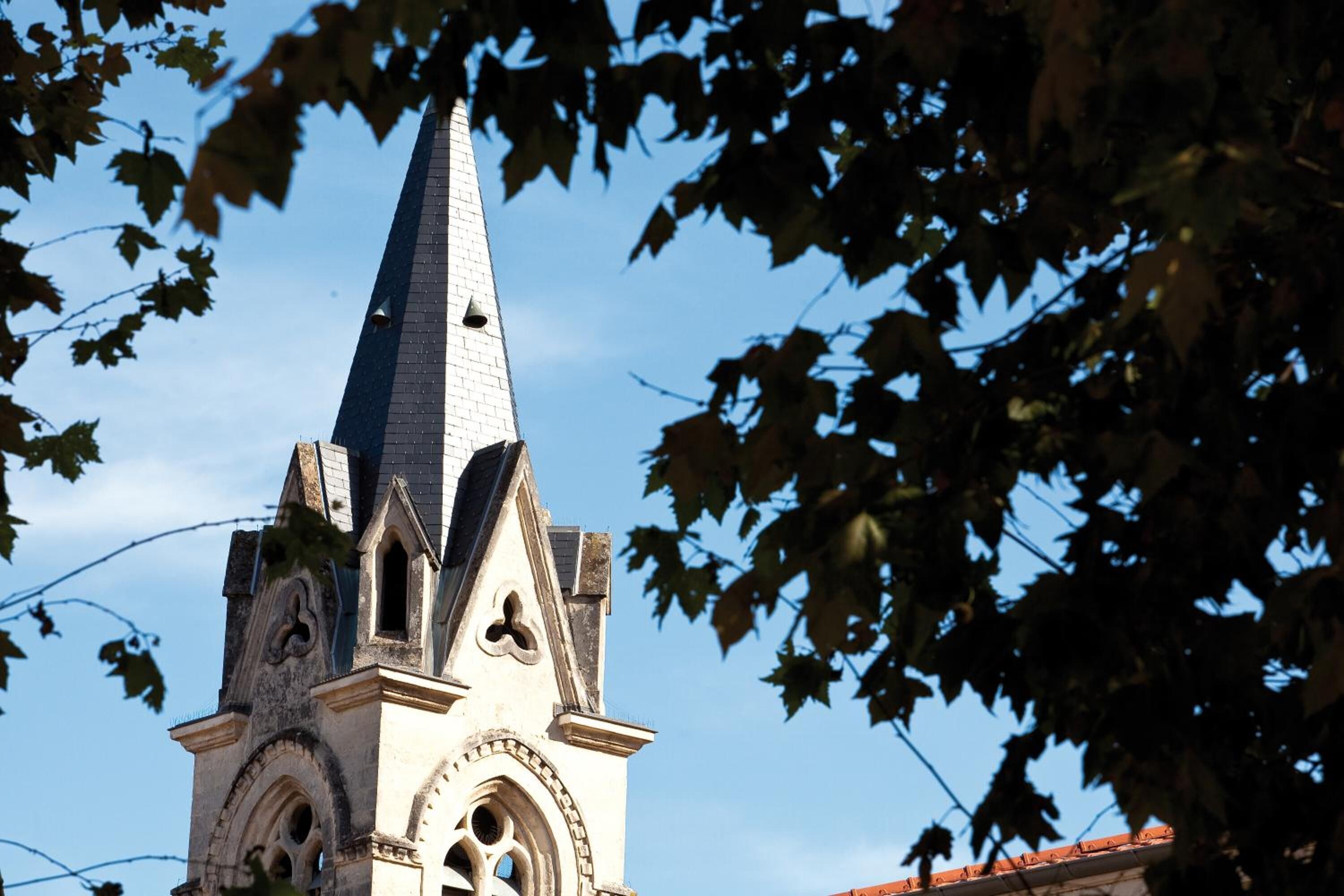 A church tower with a pointed spire and arched windows.