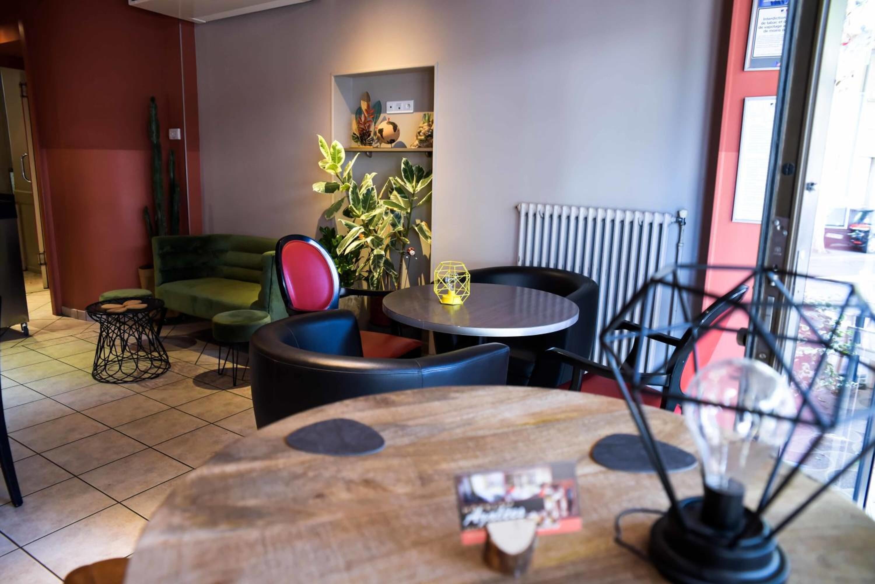 L’intérieur d’un café chaleureux, avec une table ronde en bois, un canapé vert et une chaise noire.