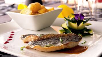 Ein Teller mit Fisch, Zitronenscheiben und einer kleinen Schüssel Kartoffeln.