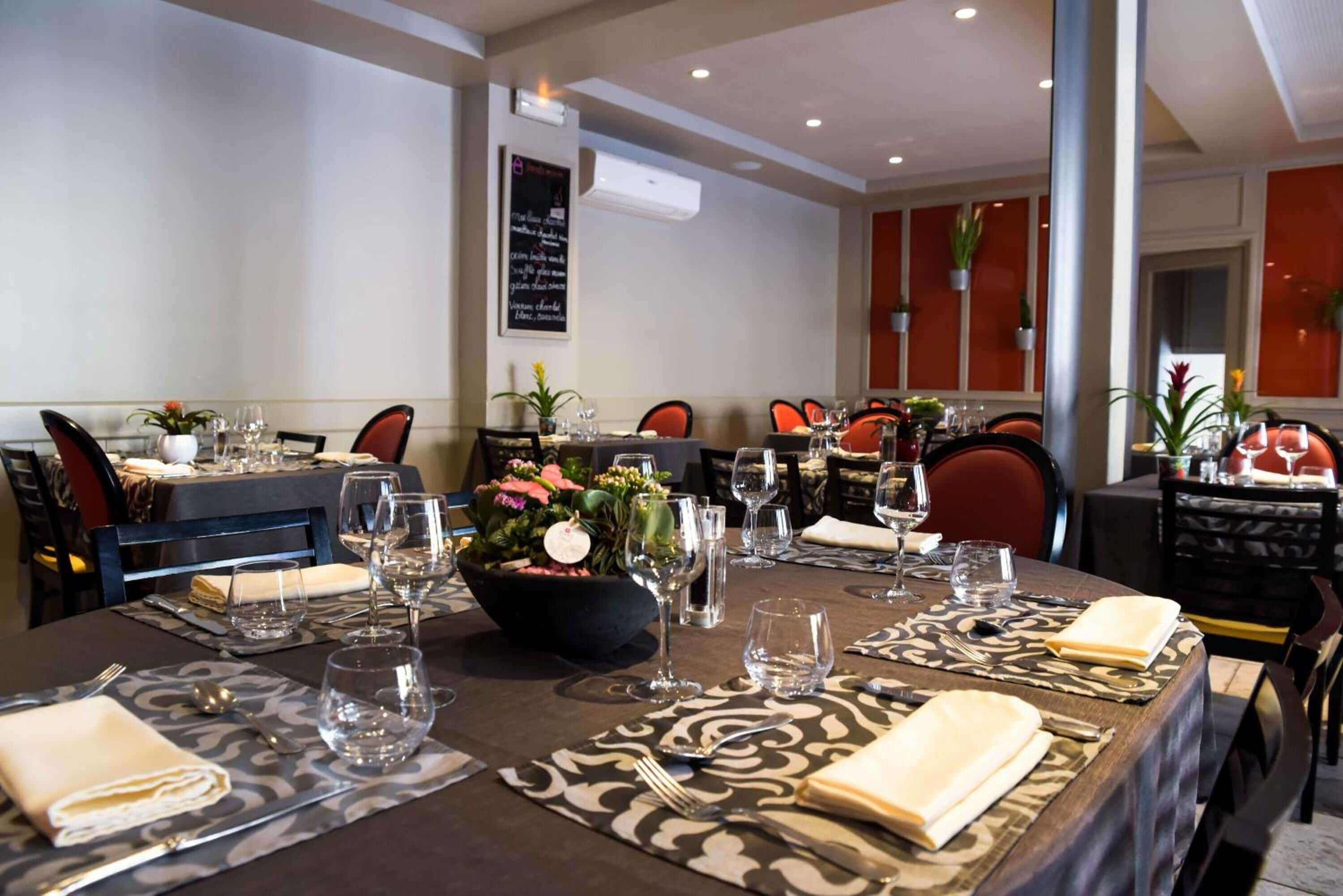 A restaurant with a long table set for dining, chairs, and a decorative centerpiece.
