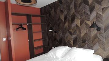 A bedroom with a bed, a wardrobe, and a wall with a herringbone pattern.