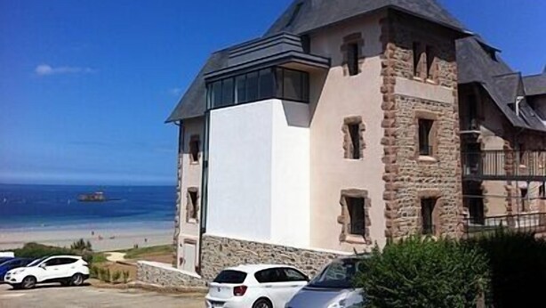 Un bâtiment qui ressemble à un château, avec vue sur la plage, des murs en pierre et une façade blanche.