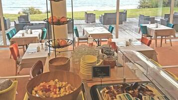 A buffet area with a view of the sea, featuring a variety of food items and a sign indicating 'Pan Breton'.