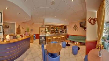 A bar area with stools, a counter, and a seating area with a sofa and tables.