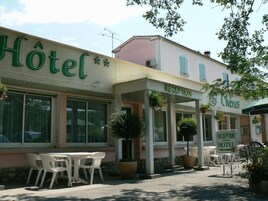 Un hotel con recepción, mobiliario exterior y plantas en macetas.