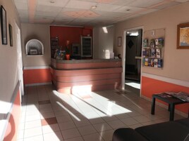 Zona de recepción con mostrador, un tablón de anuncios y suelo de baldosas.