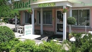 A hotel reception with a signboard, outdoor seating, and a small garden area.