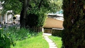 A pathway leading through a garden with a wooden fence and a tree on the right.