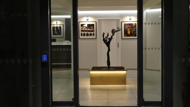 Ingresso di un hotel con reception, una scultura nera e opere d'arte appese alle pareti.
