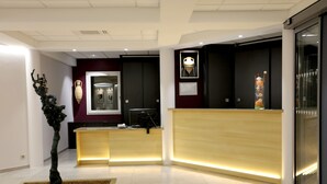 Una moderna area reception con scrivania in legno, una scultura decorativa e un quadro appeso alla parete.