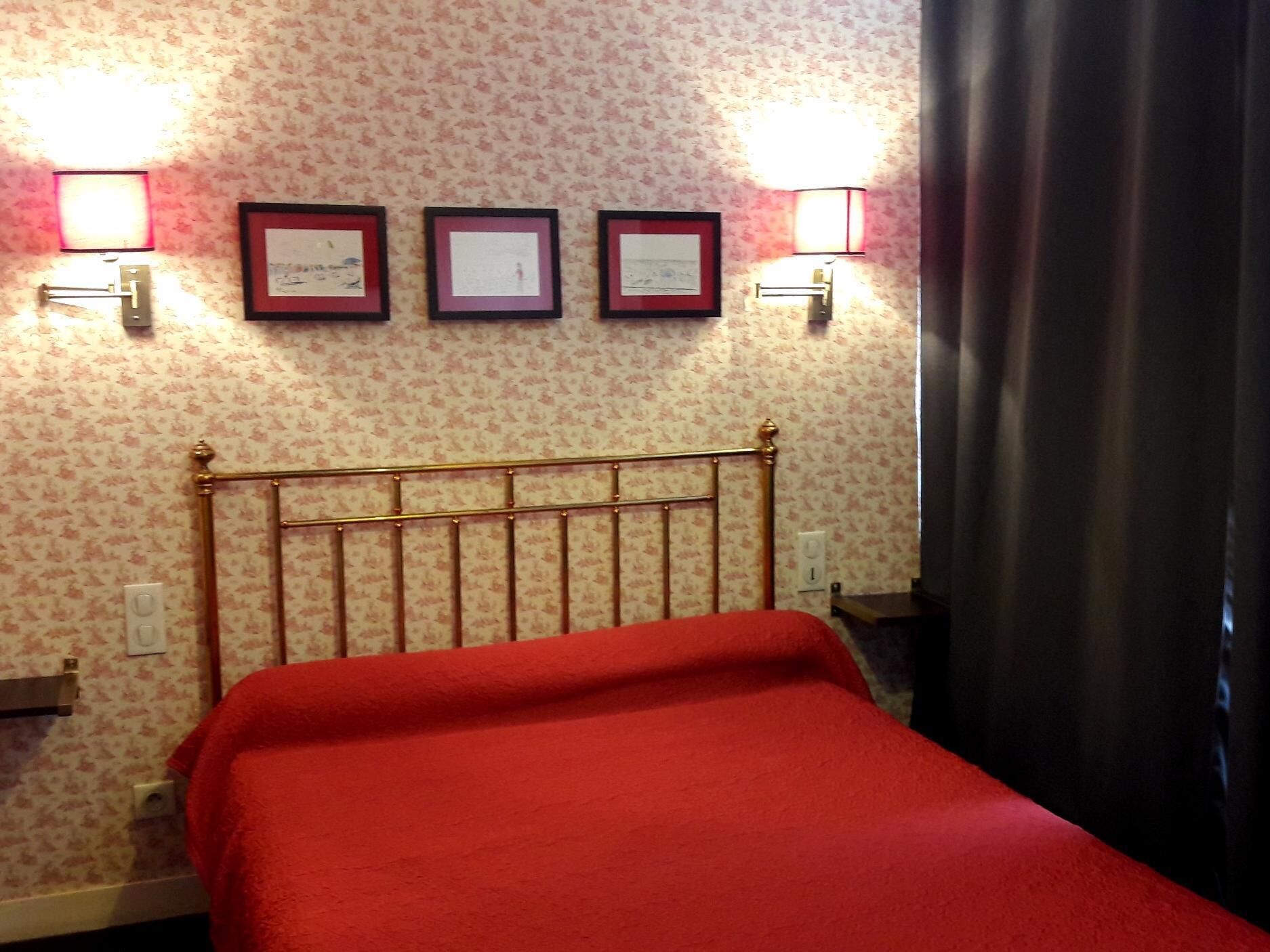 Una habitación de hotel con una cama, cabecera y tres certificados enmarcados en la pared.