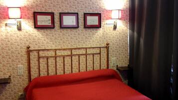 Una habitación de hotel con una cama, cabecera y tres certificados enmarcados en la pared.