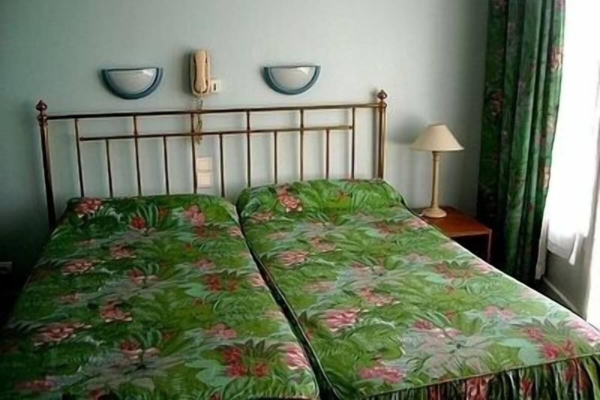 A room with a bed, a bedside table, a lamp, and a wall-mounted telephone.