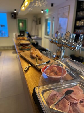 Een buffetopstelling met diverse gerechten, waaronder een schotel met ham en een kom met eieren, in een goed verlichte ruimte.