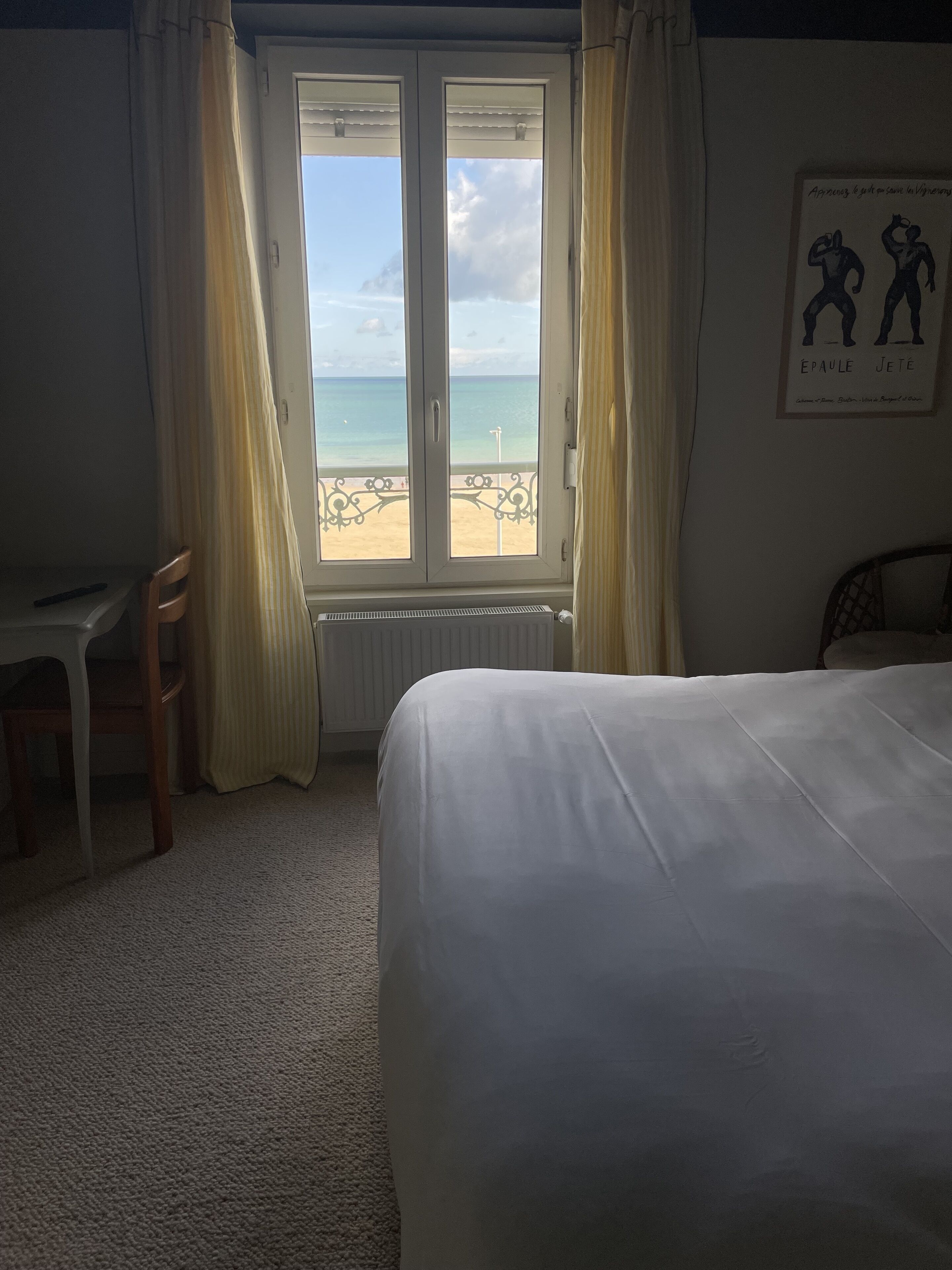 Una habitación de hotel con una cama, un escritorio y una ventana con vista a la playa.