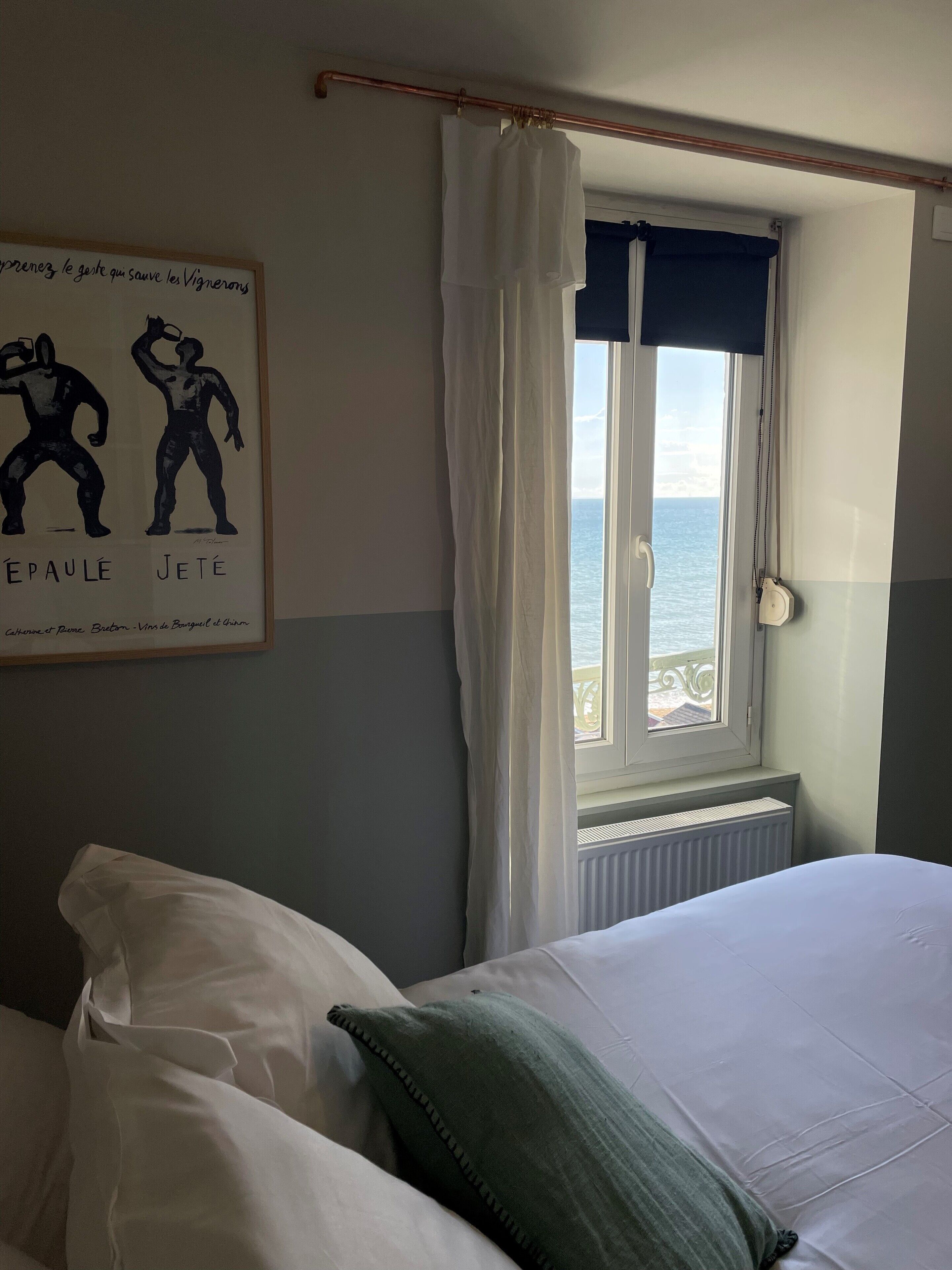 A bedroom with a bed, a window with curtains, and a poster on the wall.