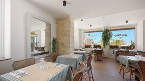 A restaurant with checkered tablecloths, wicker chairs, and a stone wall. - Le Beau Rivage (Luc-sur-Mer)