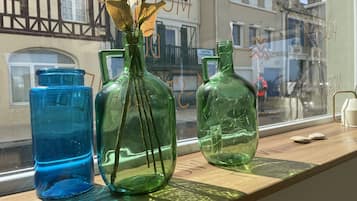 Three glass vases with dried leaves on a wooden shelf by a window.