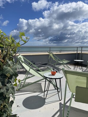 A terrace with green chairs and a table, overlooking a beach and the sea. - Le Beau Rivage (Luc-sur-Mer)