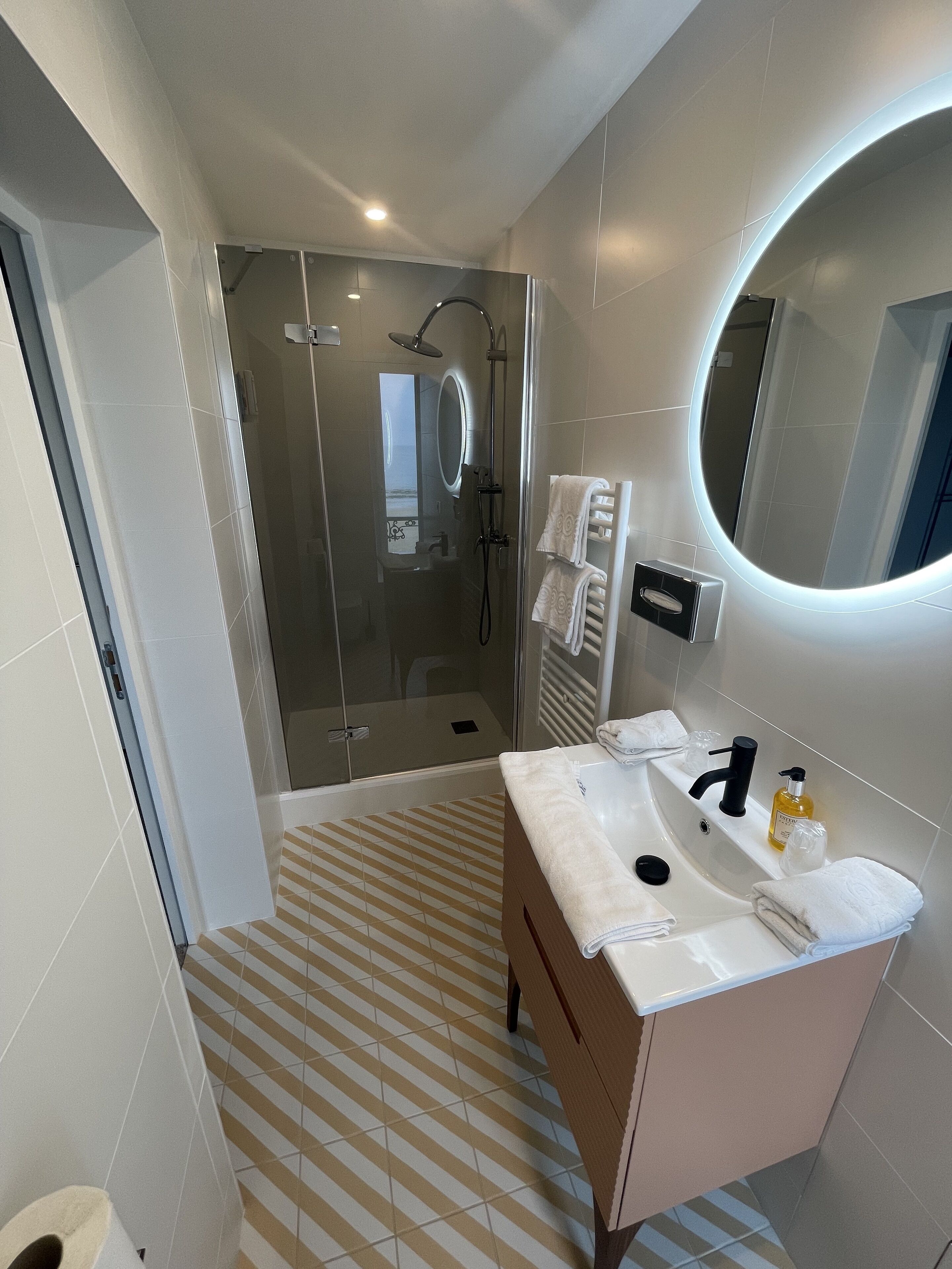 Une salle de bain moderne avec une douche à parois de verre, un meuble-lavabo avec un évier et un miroir, et un carrelage décoratif.
