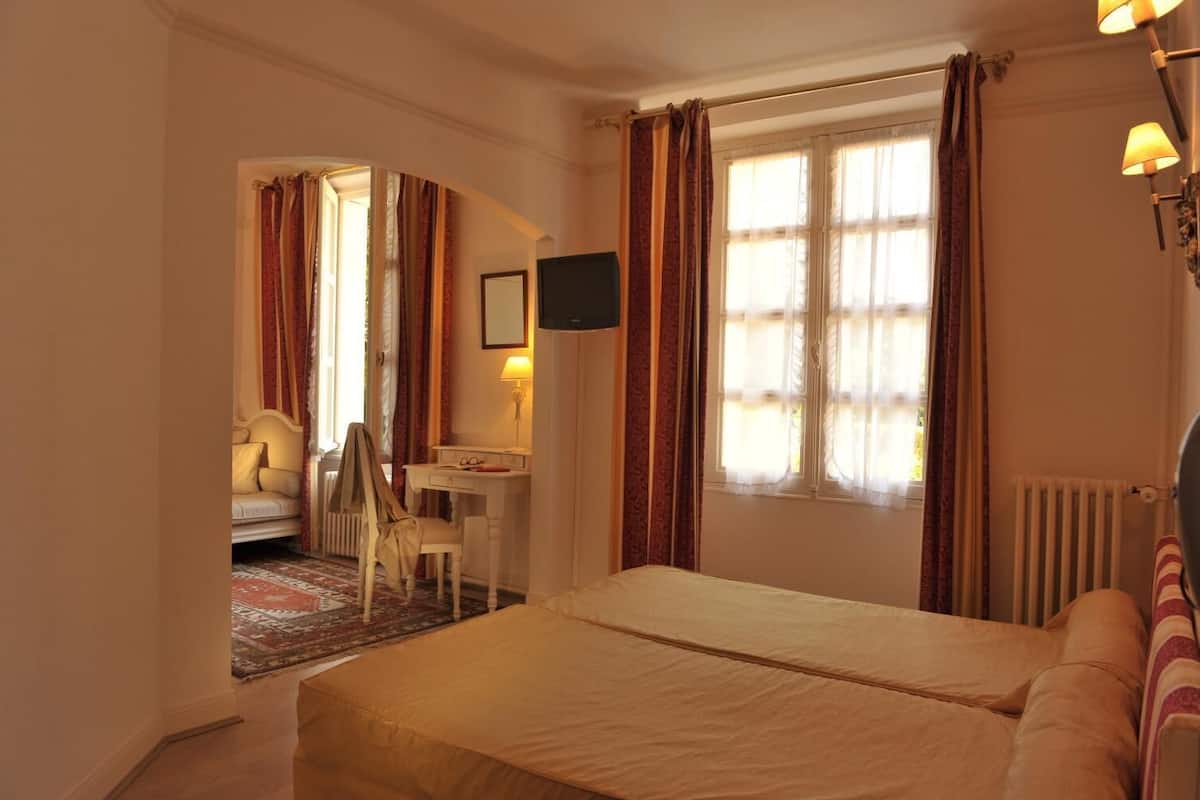 A hotel room with a bed, a desk, a chair, and a television.
