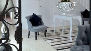 A modern living room with a staircase, a framed abstract painting, a potted orchid, and a grey armchair. - Hermitage (Buzancais)
