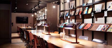 A modern conference room with a long table, chairs, and bookshelves with books.