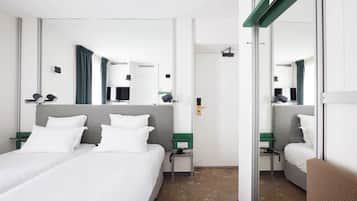 Una habitación de hotel con una cama grande, un escritorio, una silla, un televisor y un espejo.