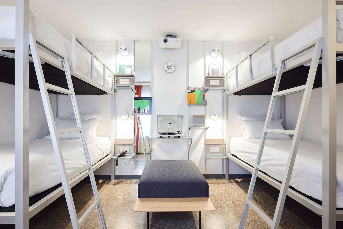 A compact room with bunk beds, a desk, and a small table.