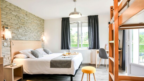 Un dormitorio moderno con cama, mesita de noche, lámpara y vistas al exterior.
