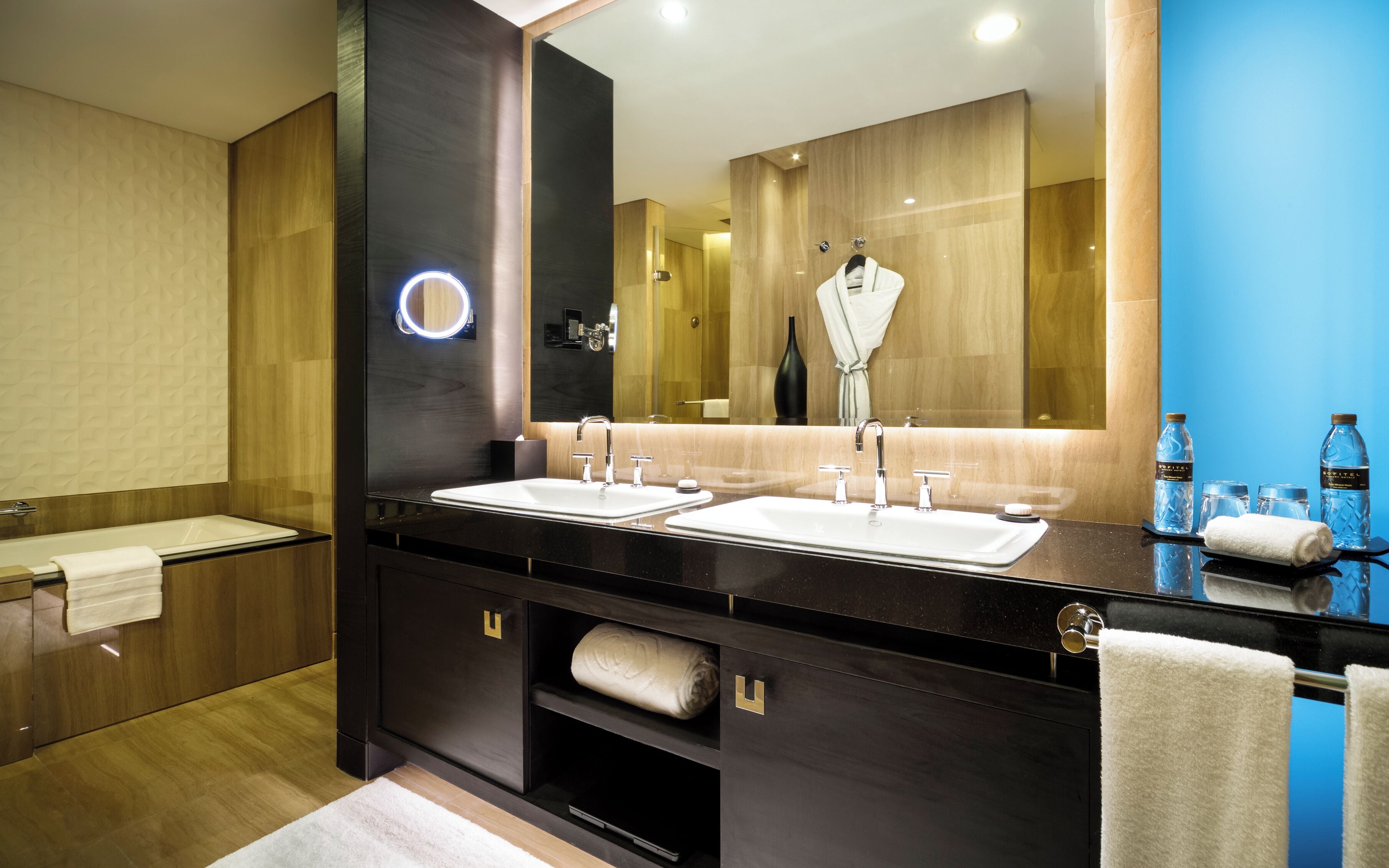 Une salle de bain moderne avec deux lavabos, un grand miroir et un porte-serviettes.