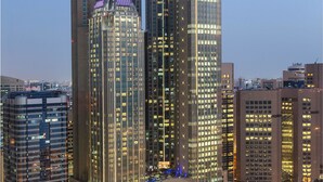 Un edificio de gran altura con un diseño arquitectónico moderno, que destaca por una aguja prominente y ventanas iluminadas.