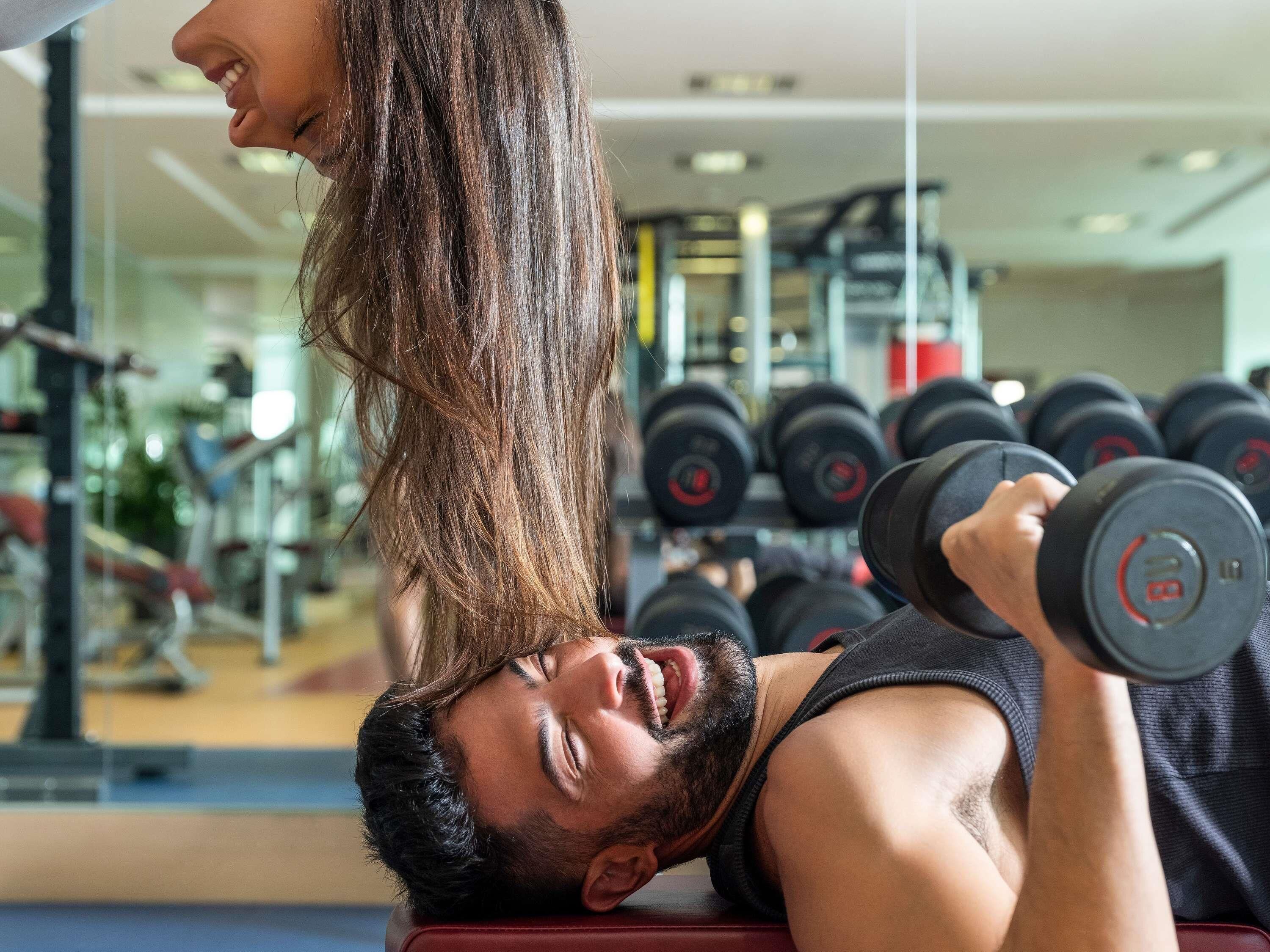 A gym with exercise equipment and a person lifting weights.