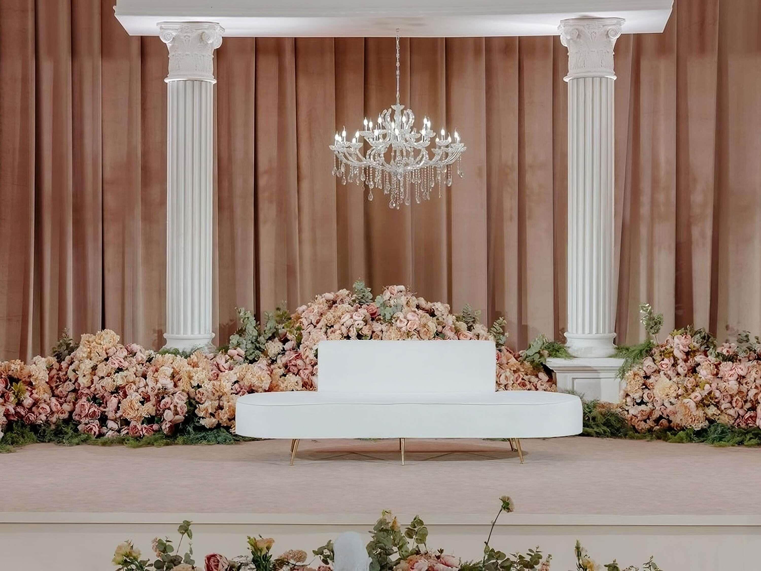 Un escenario con una plataforma blanca, columnas y un candelabro.
