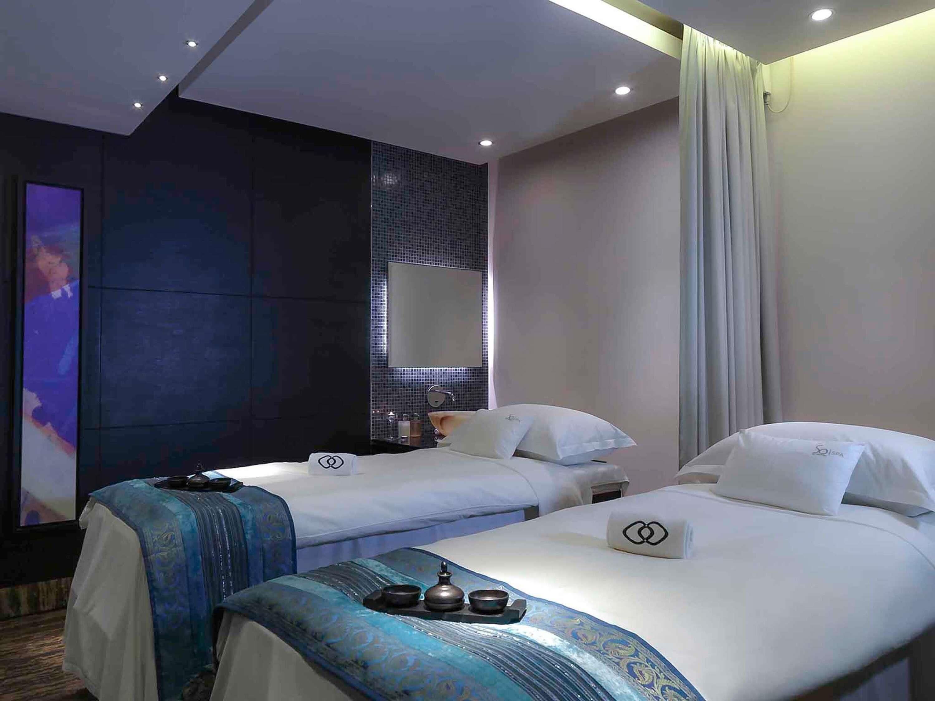 Ett hotellrum med två sängar, en stor spegel, en TV och en minibar.