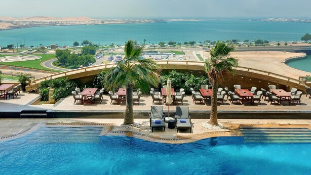 Zona junto a la piscina con mobiliario exterior y vista al mar.