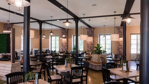 Un restaurante espacioso con techos altos, paredes de ladrillo visto y numerosas mesas y sillas.