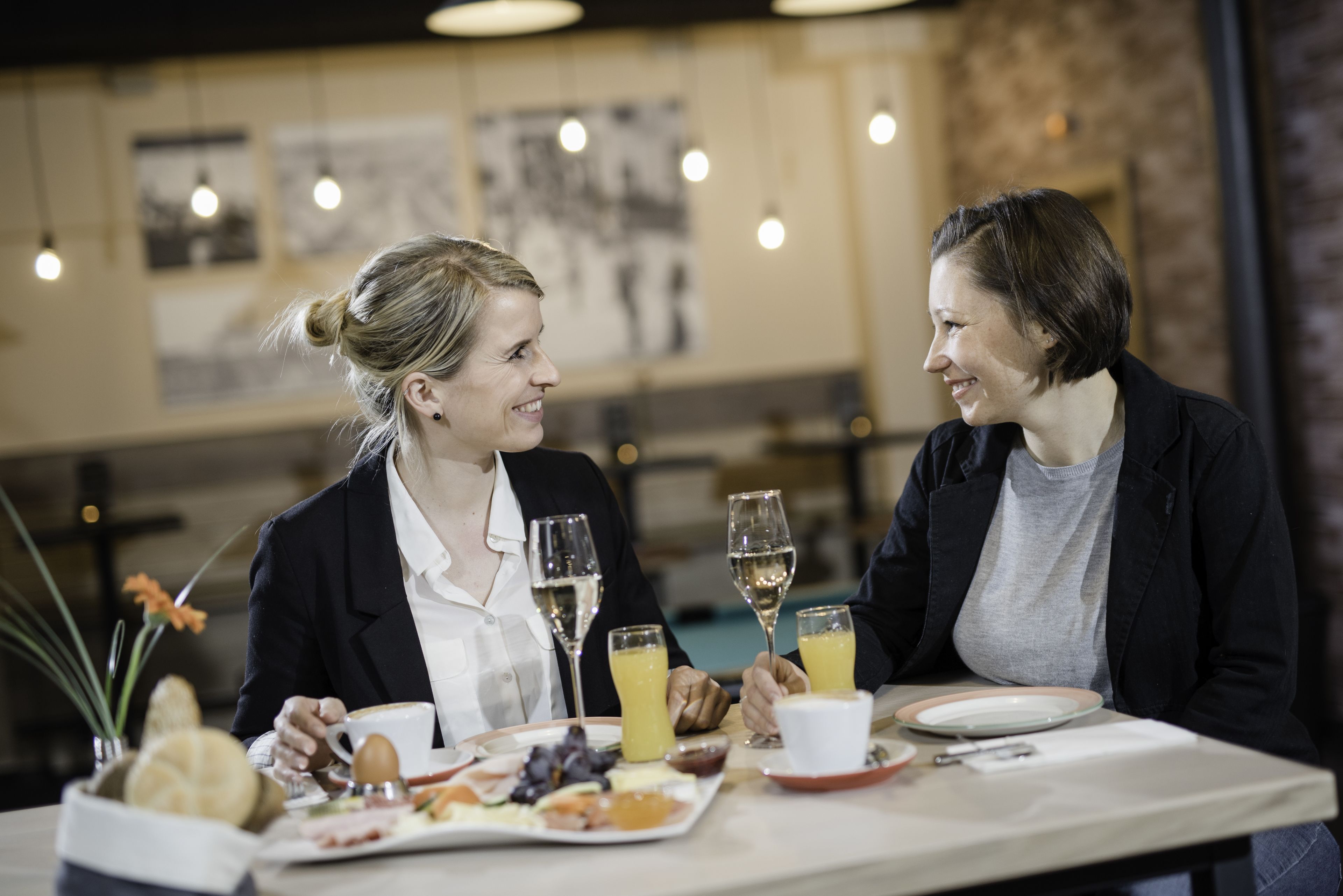 Dos personas cenando en una mesa con diversos alimentos y bebidas.
