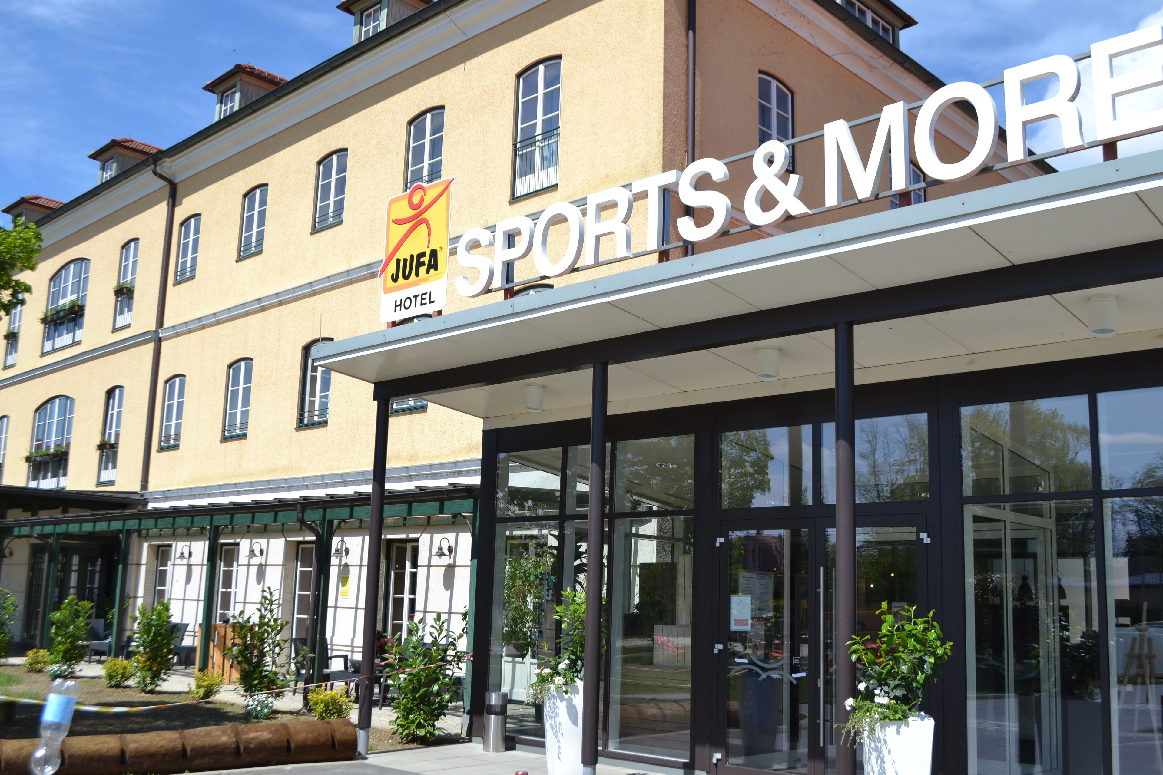 A hotel entrance with a sign reading "JUFA Sports & More Hotel."